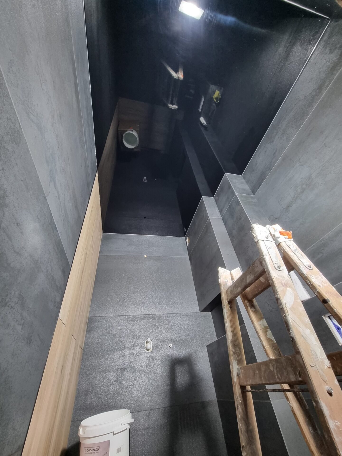 Nowoczesna klatka schodowa – czarne napinane sufity Kraków z matowym wykończeniem i betonowymi ścianami.