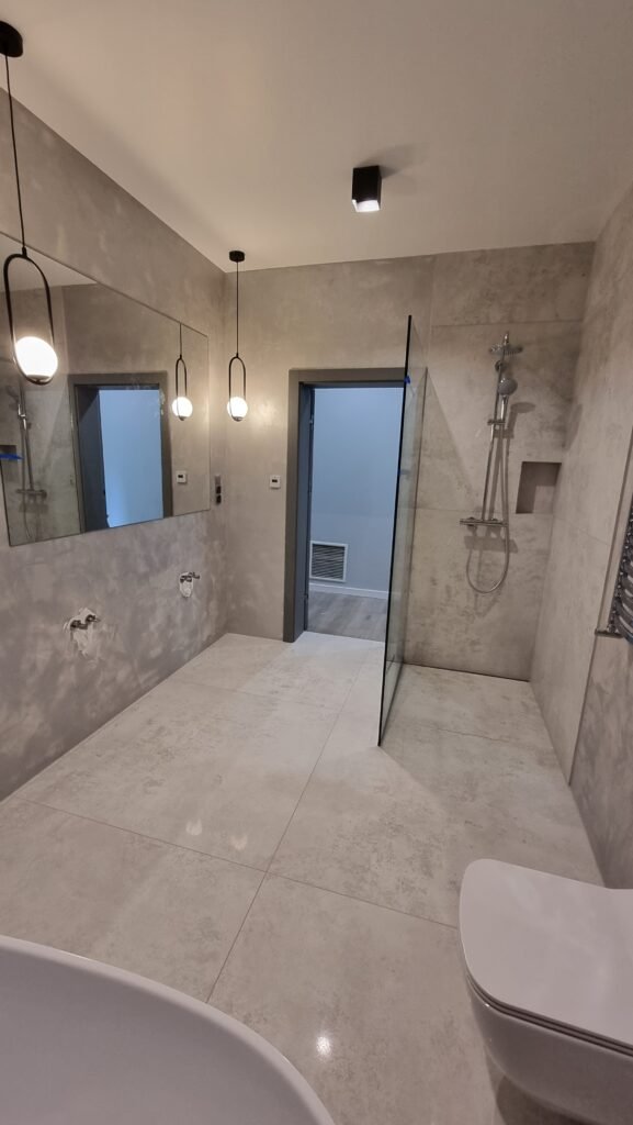 Nowoczesna łazienka w marmurze – jasne tynki dekoracyjne w Krakowie oraz biały sufit napinany z oświetleniem punktowym.